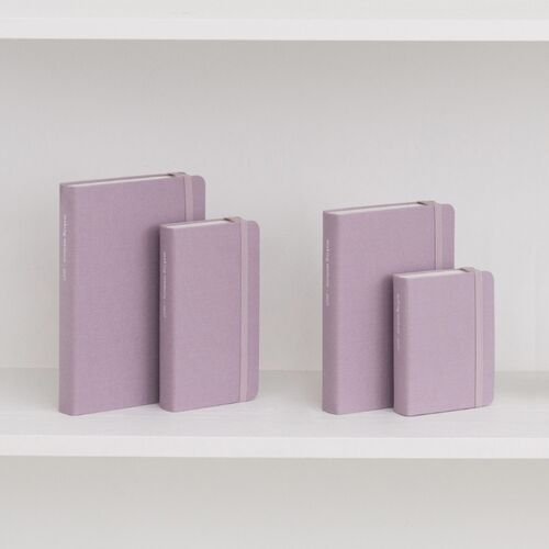 A Natural Beige planner rests on stacked Modern Navy and Ice Blue books in a desk-style setting.