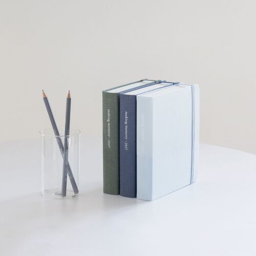 Hunter Green and Natural Beige planners are shown with ribbon bookmark pieces and matching cover-toned accessories.