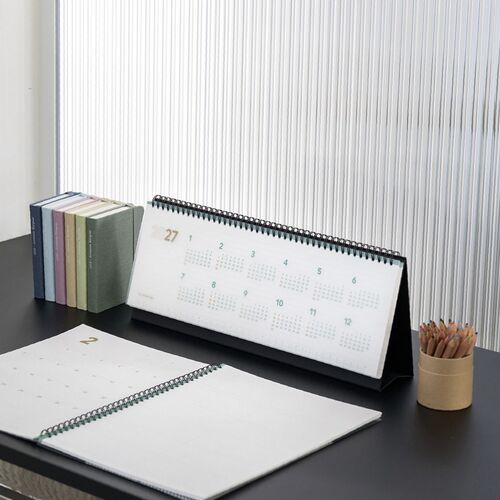 The calendar rests on a green chair with its full-year overview open and its black base clearly visible.