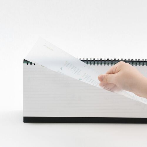 A desk scene pairs the calendar with books and stationery, showing how its broad format fits a workspace.