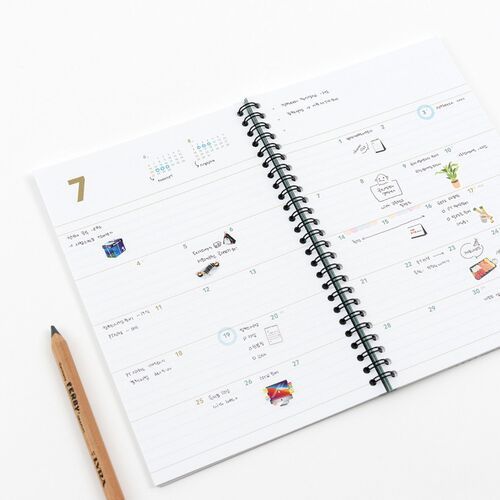 An angled spread highlights the monthly layout, colored number accents, and roomy lines for appointments or journaling.