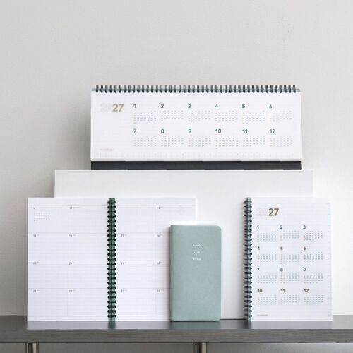 A styled shelf scene places the planner among other 2027 formats, highlighting its medium size and upright presentation.