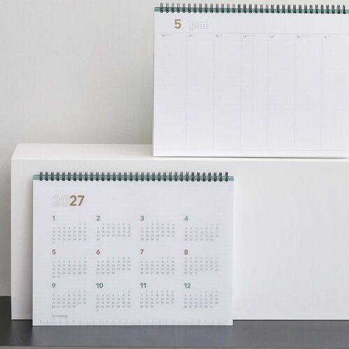 A wide display scene shows the 2027 planner on a wooden shelf with its spiral top and full-year calendar visible.