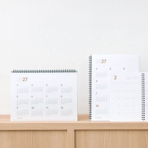 The planner stands open on a shelf with a monthly page visible, demonstrating its clean presentation for a workspace.