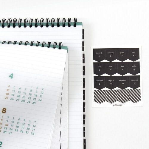 The planner is shown beside related stationery, emphasizing its broad page size and practical horizontal writing format.