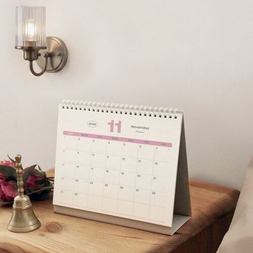 The October page stands on a shelf with warm neutral surroundings, showing the calendar’s clear monthly layout.