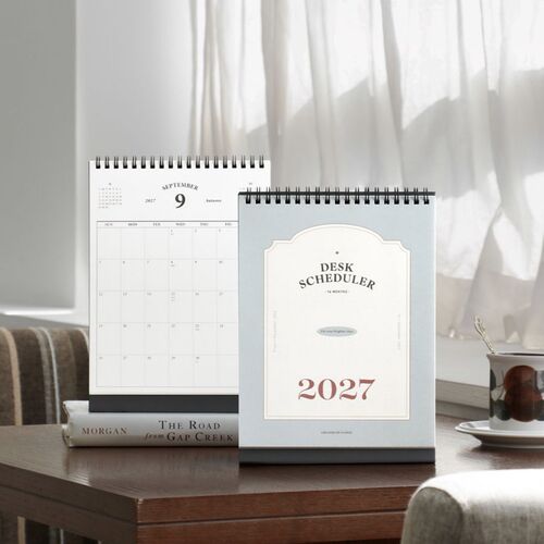 Three freestanding schedulers display monthly pages with clean borders, black stands, and generous writing areas.