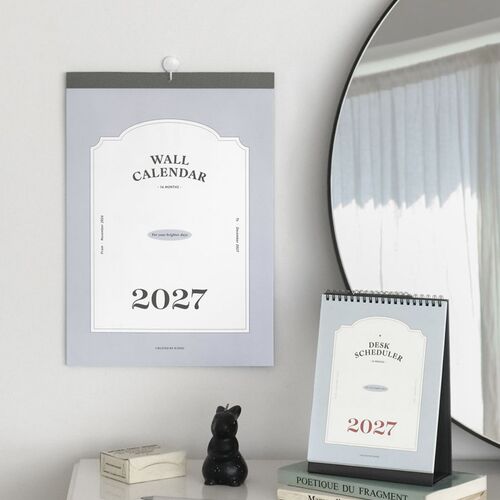 A wall calendar and desk scheduler share a shelving display, offering two clear ways to view monthly plans.