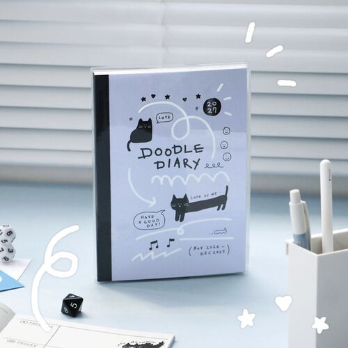 A Black planner rests on a sunlit desk, showing its starry cover design and white lettering.