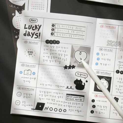 The open Black planner displays a detailed weekly layout with task lists, illustrations, and spacious writing sections.
