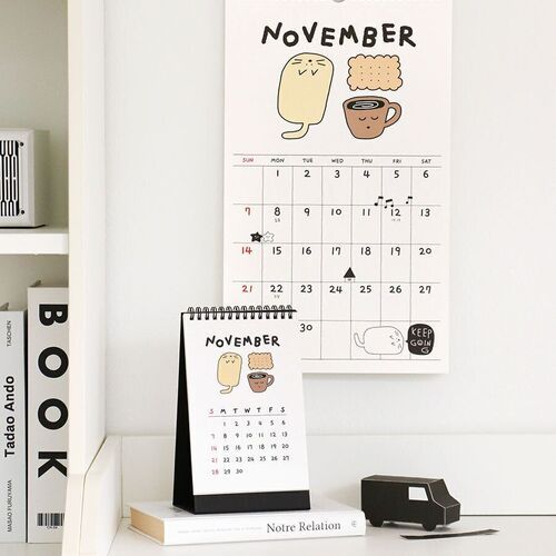 Photo 15: The November page is shown on a wall above the desk version, featuring a warm drink and seasonal illustrations.