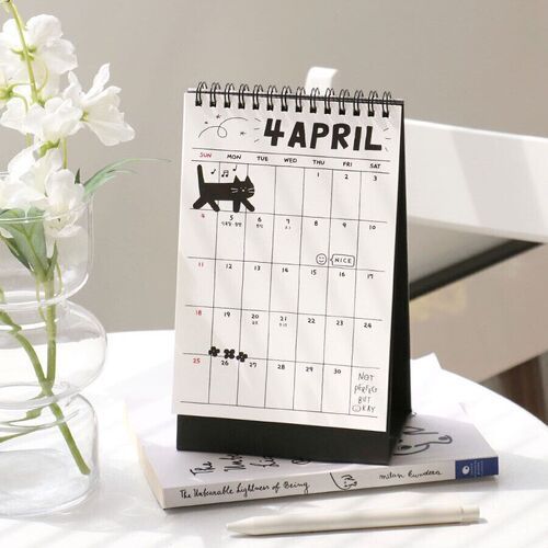 Photo 10: The April page is styled beside flowers and books, with a black cat doodle above the monthly grid.