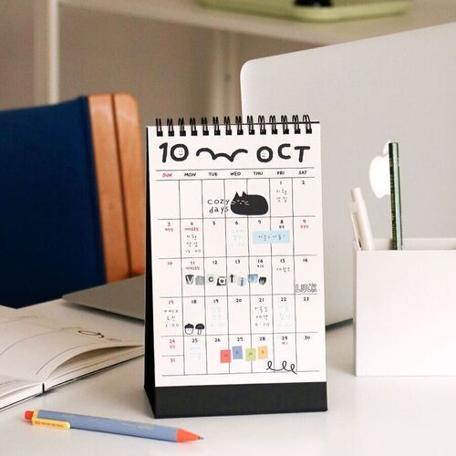 Photo 16: An October page stands beside a laptop and stationery, making the calendar’s desk-friendly format easy to picture.