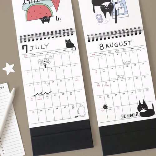 Photo 14: July and August pages show seasonal doodles, playful lettering, and broad grids arranged on black standing bases.