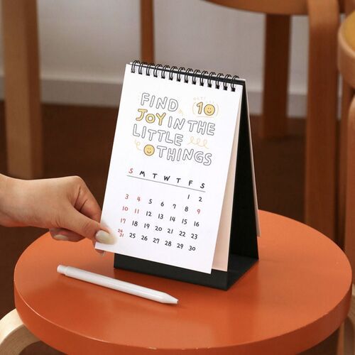 Photo 17: The calendar sits beside a small cube and notebook, with a November grid and black cat artwork visible.