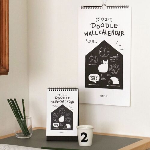 Photo 19: The cover is shown on an orange table with a white pen, emphasizing the bold black-and-white doodle design.