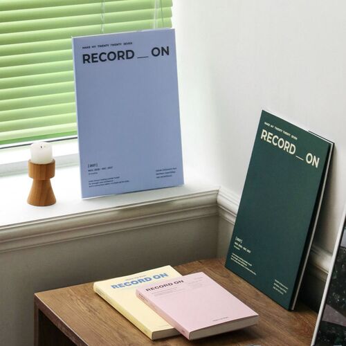 Serenity Blue and Moss Green planners stand near a bright window, showing their simple vertical A5 format.