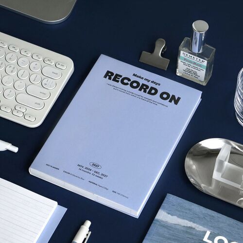 Several color options rest on a wooden table beside a pen, highlighting the slim profile and varied covers.