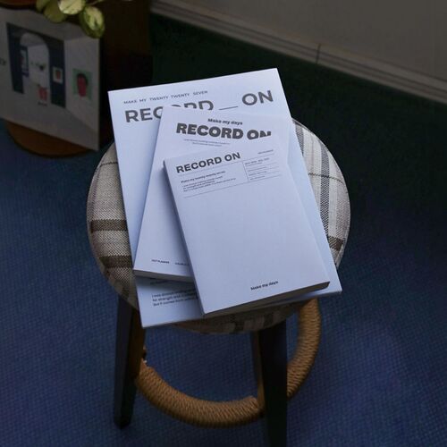 The planner is styled on a chair with other notebooks, showing its portable A5 footprint.