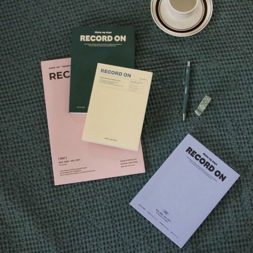 Multiple planners and writing tools are arranged overhead, comparing the four cover styles by color.