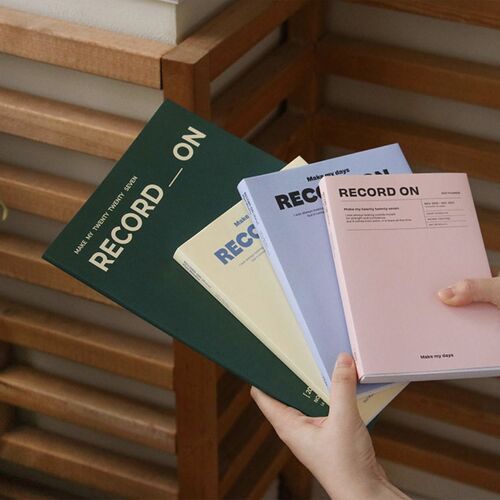 A hand pulls the Serenity Blue planner from a shelf, highlighting its manageable size and smooth cover.
