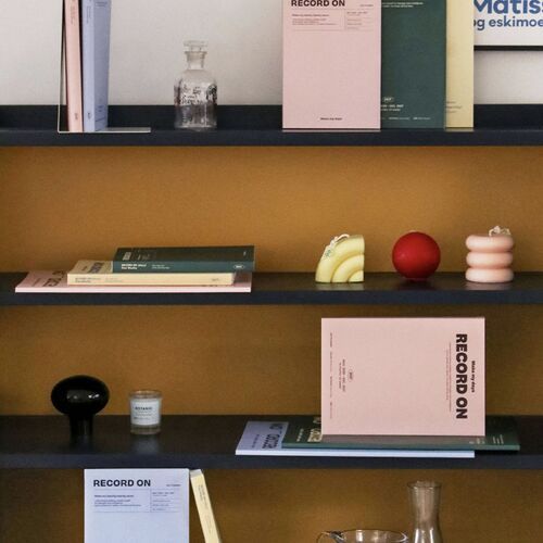 Stacked planners rest on fabric with a coordinating pen, showing their slim bound construction from above.