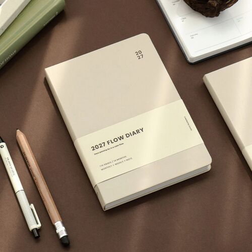 Cloudy Blue stands upright with its printed belly band, while writing supplies frame the cover in a neat desk scene.