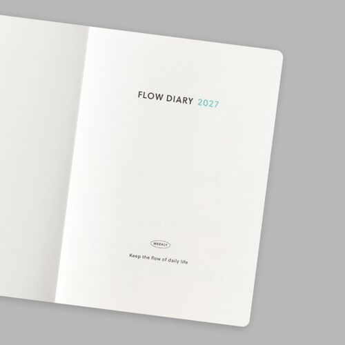 A partially open planner reveals its pale endpaper, rounded page corners, and clean flat-opening construction.