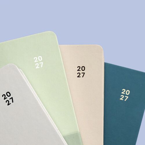Pistachio and Beige covers are layered against a soft blue background, highlighting their rounded corners and simple year marking.