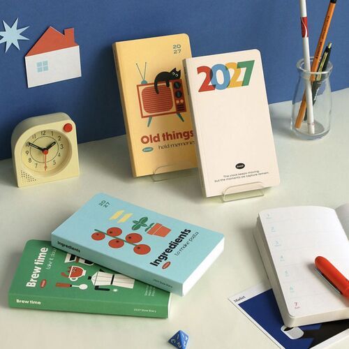 Four colorful planner styles are arranged with stationery and desk objects, showing the range of illustrated cover designs.