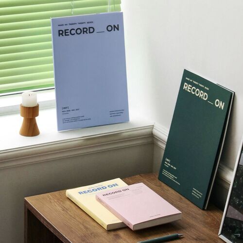 Four Record On planners are arranged as a colorful stack, showing Butter, Misty Pink, Serenity Blue, and Moss Green covers.