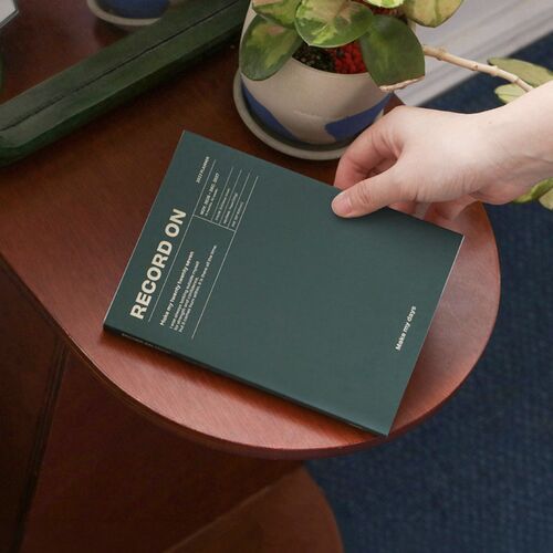 Butter planner lies diagonally across an open book, with a pen and neutral stationery arranged nearby.