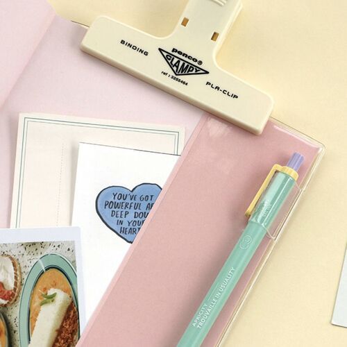 An open planner shows the flat spread and lined writing areas, with a clip holding the pages open.