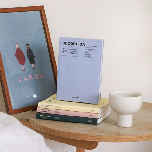 The planner collection is displayed on a stool, with the compact B6 format visible against a darker room setting.
