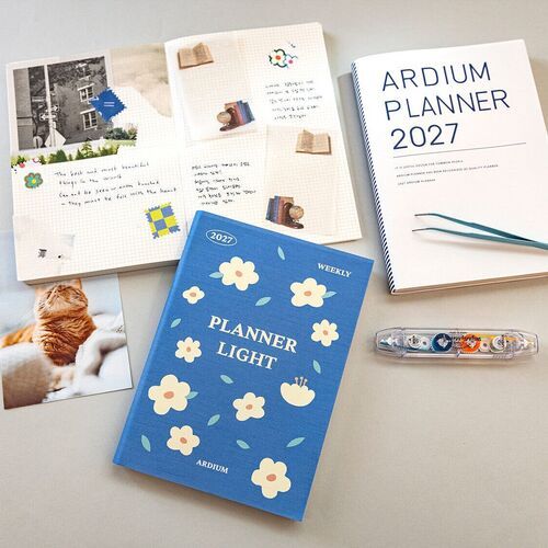 A clear PVC cover is visible over an open planner, with a patterned paper insert resting across the pages.