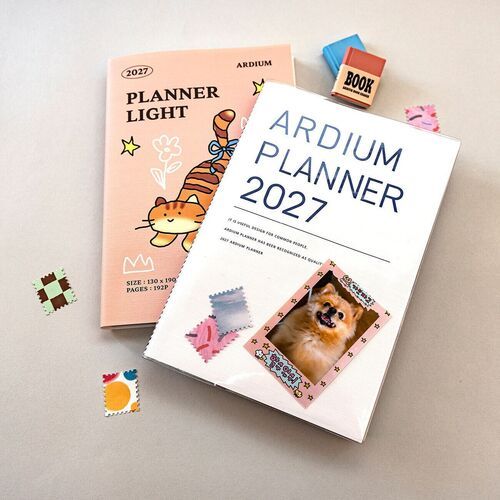 Ribbon Cat rests beside an open book and stationery, illustrating a practical reading or study setup.